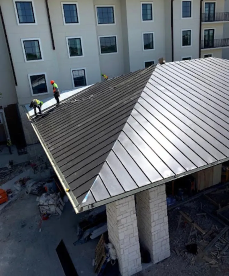 Crew installing standing seam metal roof panels on a commercial project in University Heights
